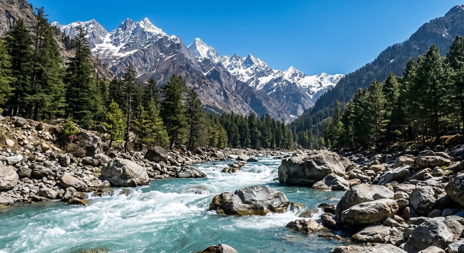 Turquoise Beas River rushing over boulders with snow-capped Himalayan peaks behind